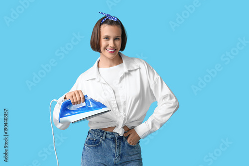 Young woman holding iron on...