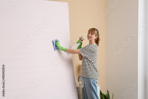 Young woman cleaning mattre...