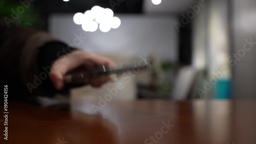 A hand grabbing and picking up a mobile phone on restaurant table
