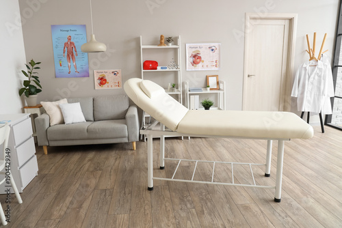 Modern medical examination room interior with treatment bed, sofa, anatomical...