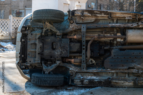 фотографія A detailed medium shot of the undercarriage and front suspension of an overturned SUV after a road accident