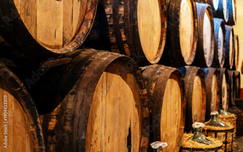 Rows of wooden oak barrels in a wine cellar.