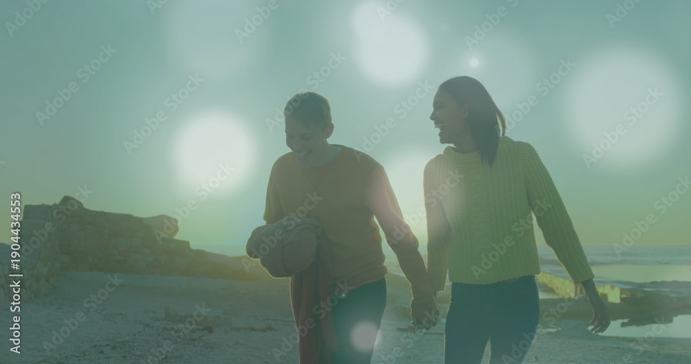 Obraz premium Image of light spots over caucasian couple at beach