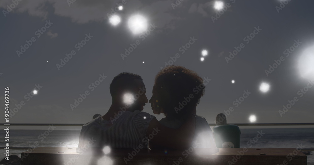 Naklejka premium Image of glowing spots of light over african american couple embracing each other at the beach