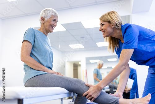 Fotografie Physiotherapist examining senior woman knee