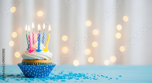 Birthday cupcake with colorful candles and blue sprinkles