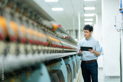 Fotografi Engineer in factory workshop holding tablet to inspect textile machinery