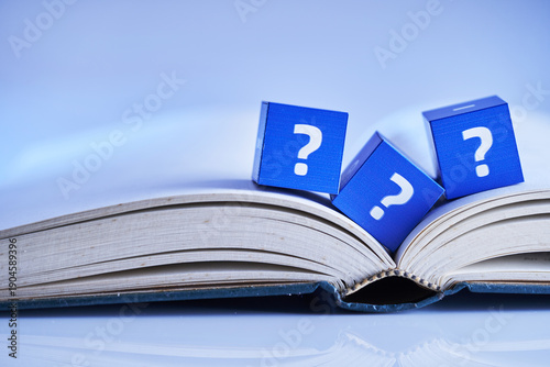 cube block with question mark on opened book