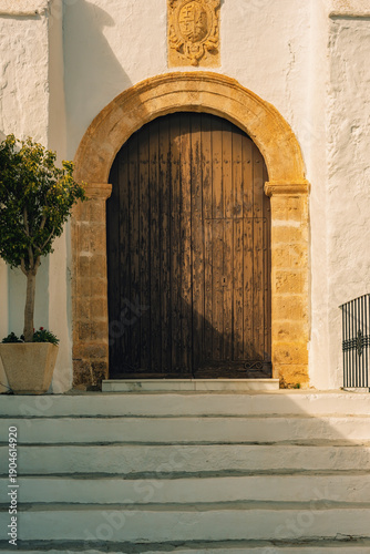 Принти на полотні Old wooden door with steps of an ancient spanish andalusian church with white stucco walls
