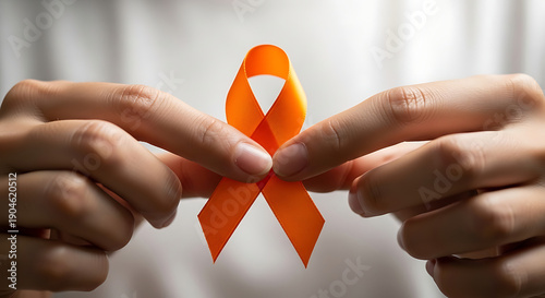 A person holds an orange awareness ribbon, symbolizing support for various health conditions like multiple sclerosis