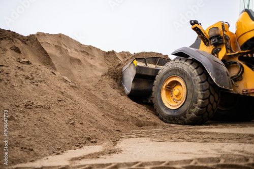 Wheel loader collecting sand for construction site
