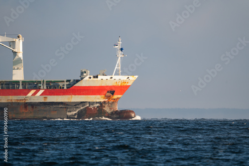 Close up of the rusty bow of a large cargo ship sailing through the blue waters of the Baltic Sea