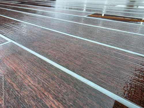 Obraz na plátně Closeup of sunlight glistening of of a yachts wet teak deck