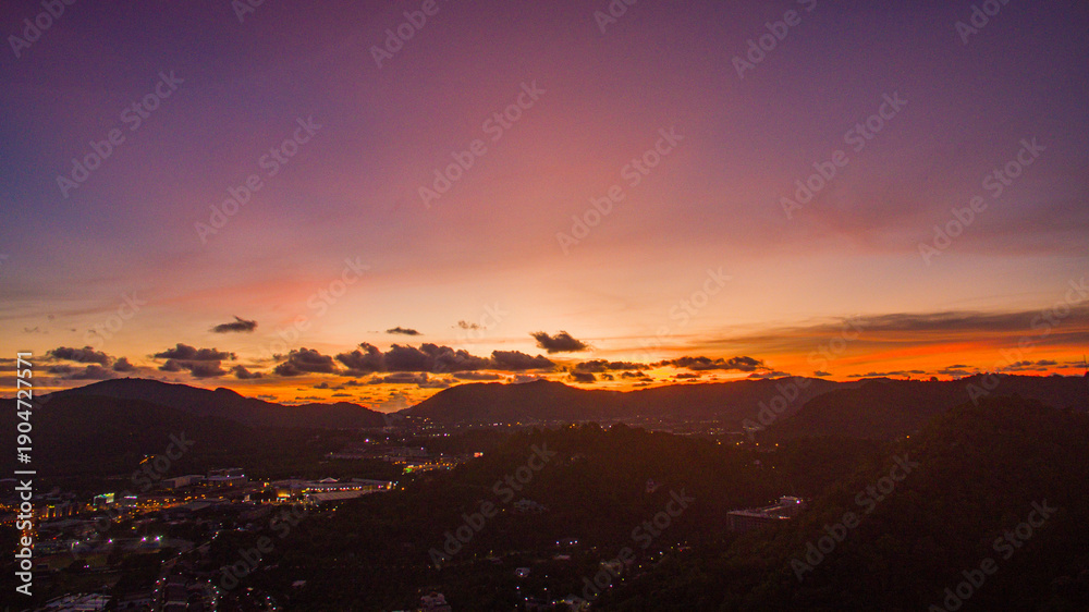 Fototapeta premium Aerial view of scenery Khao Rang viewpoint at twilight. view of a town nestled among lush green mountains at sunset, with a Pavilion structure perched on the hillside at Phuket town at Dusk