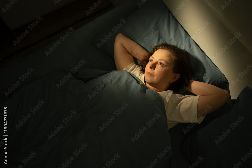 Obraz premium Brainstorming middle-aged woman with open eyes lying in bed, suffering from insomnia and sleep disorder