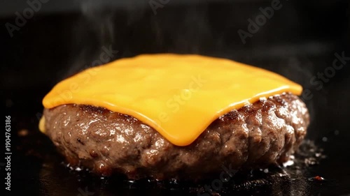 Close-up view of a sizzling beef burger patty topped with melted cheese on a hot grill, captured from an overhead angle, highlighting the smoky atmosphere and juicy texture in food photography