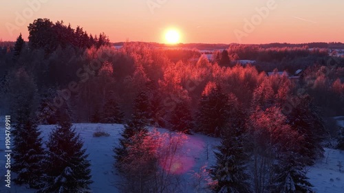 4K aerial drone left reveal of Lithuania winter forest at golden hour, vivid sunset horizon over snowy landscape, frosted trees glowing in warm cinematic light