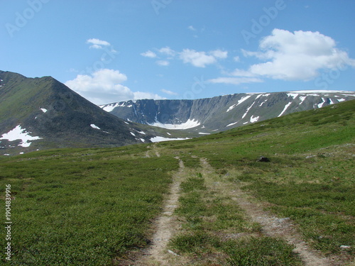 Dirt road to the mountains in summer on a sunny day