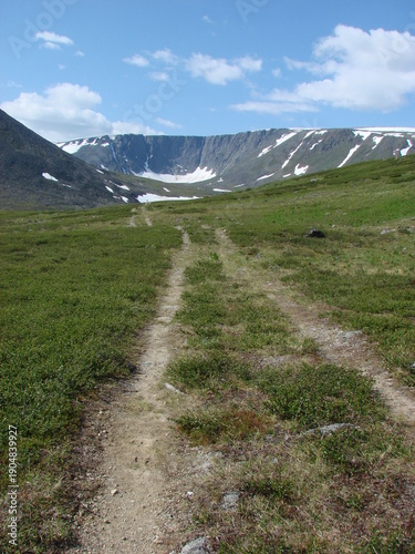 Dirt road to the mountains in summer on a sunny day