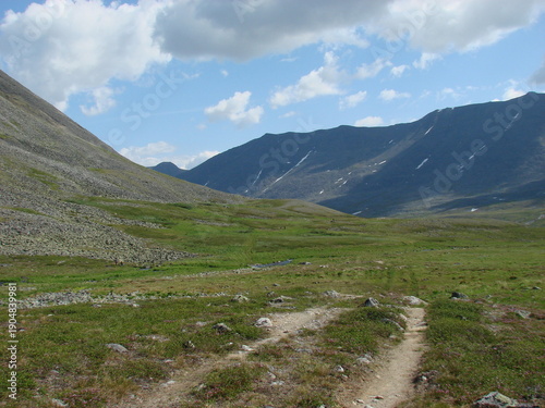 Dirt road to the mountains in summer on a sunny day