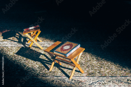 Photography Kuala Lumpur, Malaysia - January 29, 2026: Two Qurans placed on traditional wooden stands, illuminated by sunlight on patterned carpet, symbolizing reverence, study, and spirituality during Ramadan