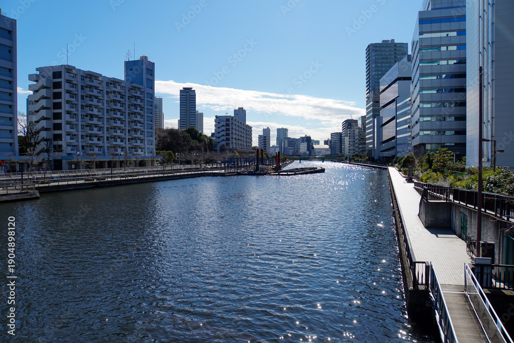 Naklejka premium 晴天の下でキラキラと光る水面が美しい都市部を流れる運河と両岸に並ぶビル群