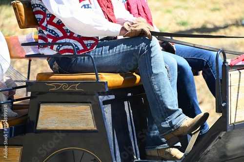 Close Up of Legs of Drivers of a Horse Cart with Patriotic  Red, White and Blue Vest on July 4th in Kern County, California
