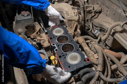 Foto Close-up of a mechanic’s gloved hands installing a new cylinder head gasket on an open engine block during vehicle repair