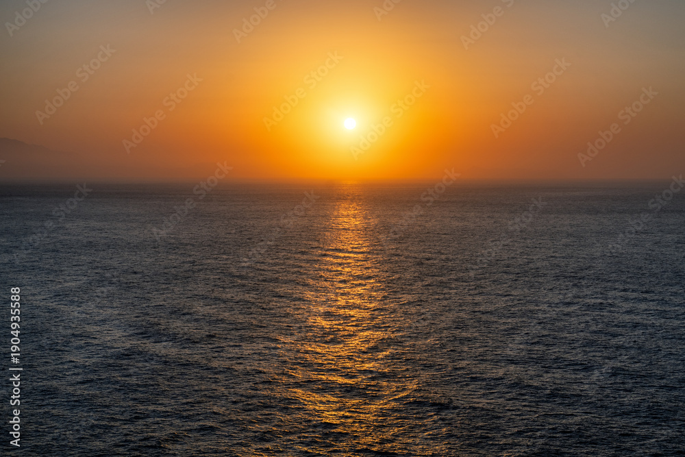 Naklejka premium Golden sunset over the Mediterranean Sea with glowing reflection on calm water