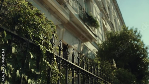 Residential building with greenery and iron fence in sunny day  