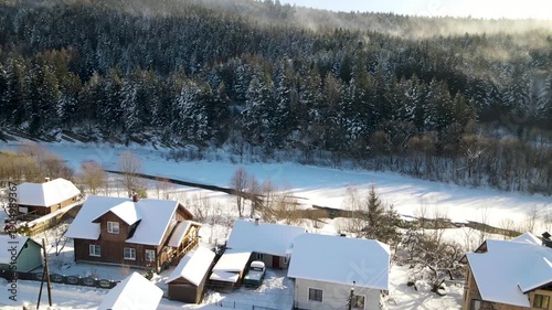 Aerial drone view of houses in a village near snow-covered mountains with pine trees in winter. Aerial panoramic drone view from above, top view from drone.  Ukraine, Carpathians, Skole city
