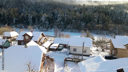 Aerial drone view of houses in a village near snow-covered mountains with pine trees in winter. Aerial panoramic drone view from above, top view from drone.  Ukraine, Carpathians, Skole city
