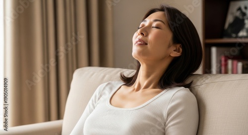 ソファに座り上を見上げてリラックスする日本人女性