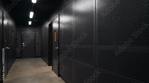 Modern recording studio interior, black soundproof walls, sound mixing desk with monitors and chair in room.