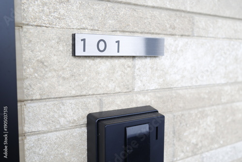 集合住宅の玄関に設置された部屋番号101の金属プレート。