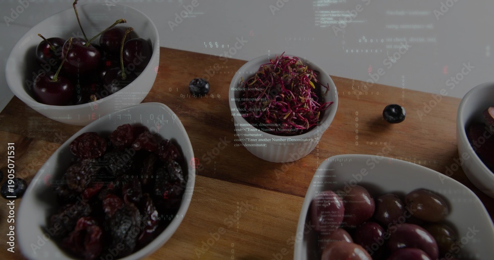 Fototapeta premium Showing wooden cutting board holding white ceramic bowls on studio tabletop, with cherries, olives