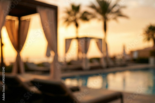 Defocused luxury resort swimming pool with cabanas and palm trees at sunset.