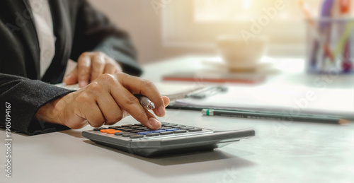 A close-up image of a professional's hand using a calculator. Strategic office workspace concepts for tax calculations, banking, investment analysis, and corporate data managemen
