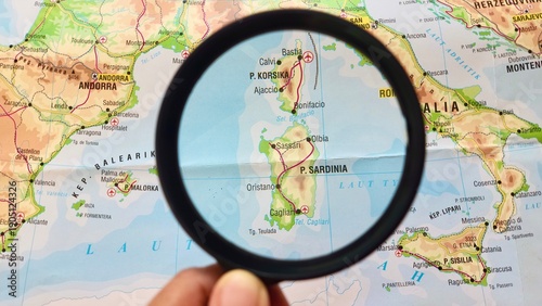 View of Sardinia Island, Corsica Island, on a geographical map of Europe, seen using a magnifying glass