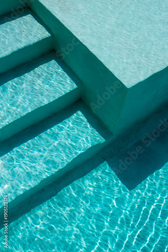 Vista detallada de una piscina con agua turquesa cristalina y reflejos de luz natural sobre superficie arquitectónica moderna. Concepto de lujo, descanso, verano y estilo de vida relajado