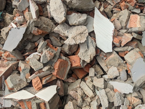 Top view of a pile of demolition waste featuring broken red bricks, concrete chunks, and shattered plaster fragments from a construction site.