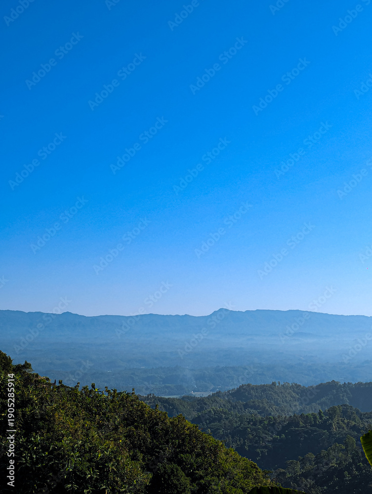 Fototapeta premium Breathtaking Mountain Landscape with Lush Green Tropical Forest and Clear Blue Sky