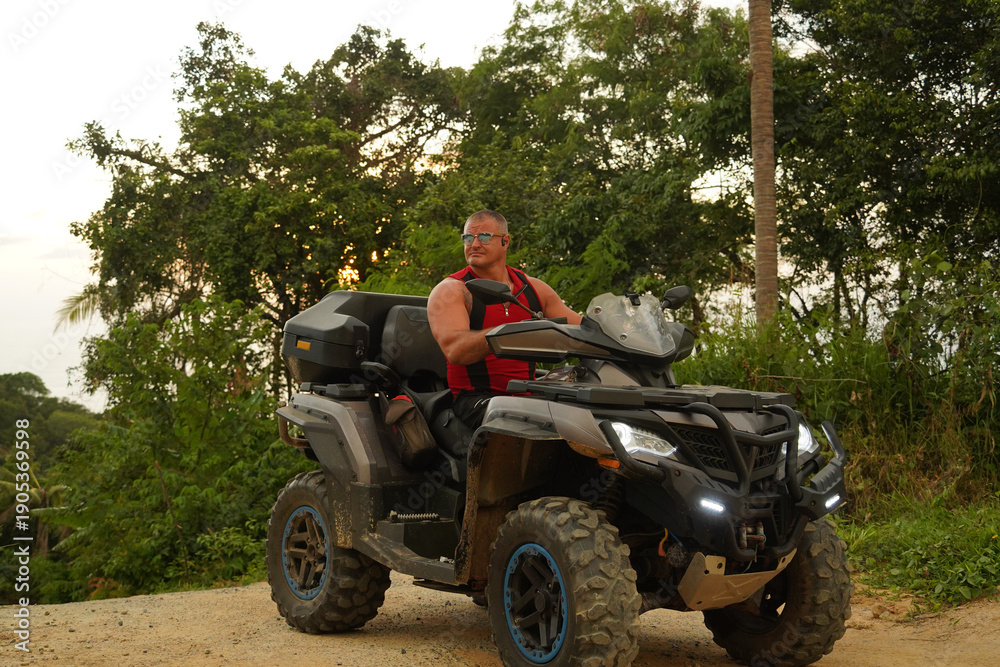 Fototapeta premium A man engages in extreme ATV riding on mountains in the evening