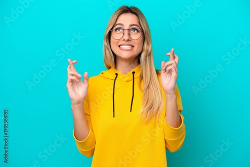 Quadro su tela Young Uruguayan woman isolated on blue background with fingers crossing and wish