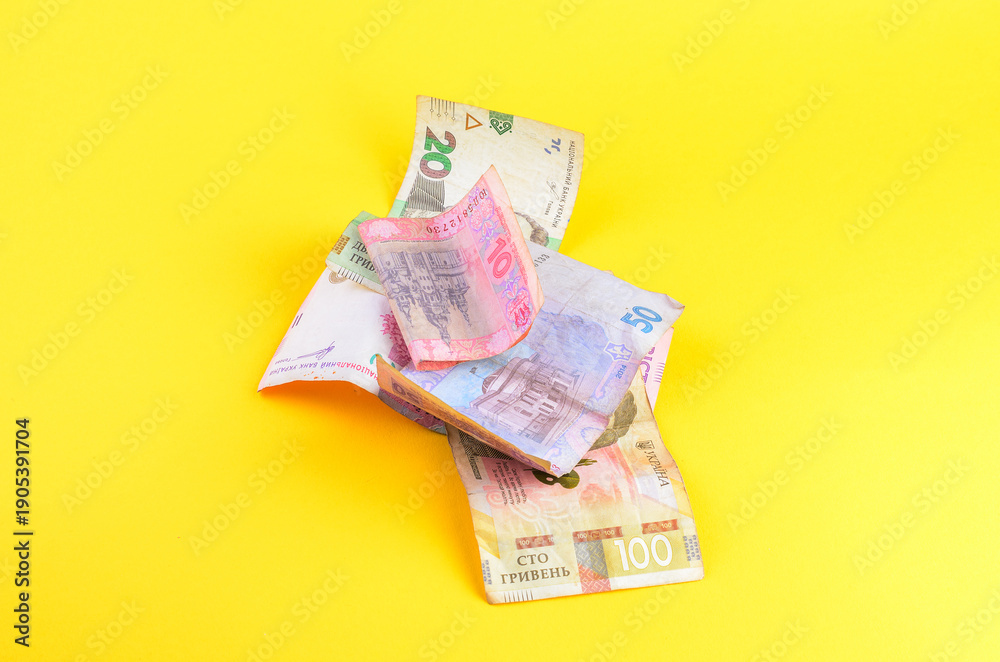 Obraz premium Pile of Ukrainian Hryvnia banknotes scattered on a bright yellow background