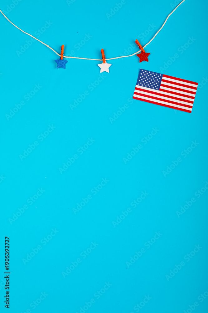 Obraz premium Stars-decorated clothespin and loose USA flag on string against a blue backdrop with space