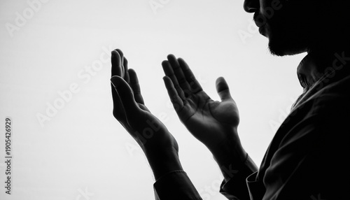 Silhouette of an individual with hands raised in earnest prayer, embodying deep spirituality and heartfelt devotion in a moment of quiet contemplation and introspection