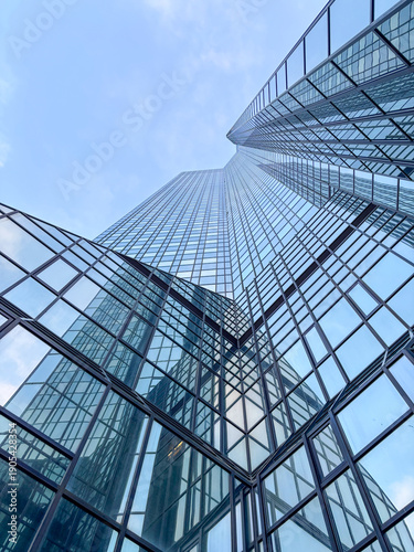 Tableau sur toile Glass skyscraper with reflections under blue sky.