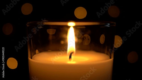 Close-up of a lit candle with bokeh lights in the background.