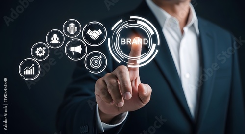 Businessman in suit pointing at digital interface showing business icons and highlighting brand focus